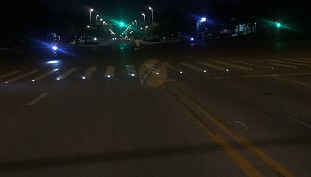 Solar-powered road studs lighting up a crosswalk at night to enhance pedestrian and vehicle visibility.